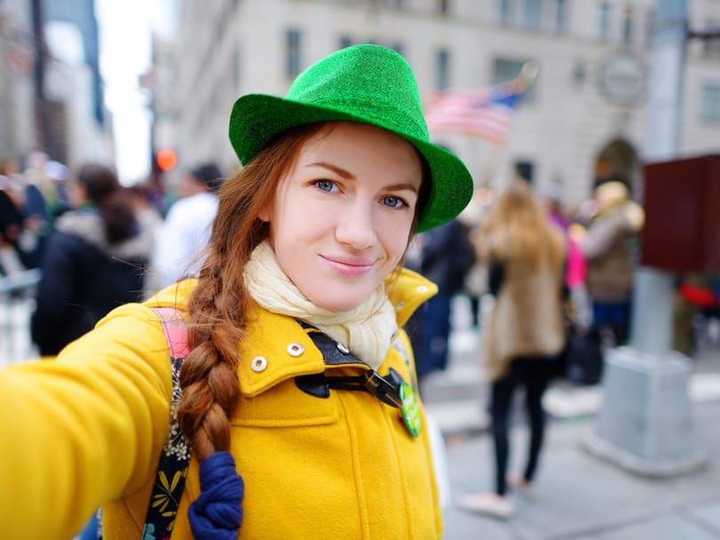 Young tourist taking a selfie with her smartphone during the annual St. Patrick's Day Parade on 5th Avenue in New York City
