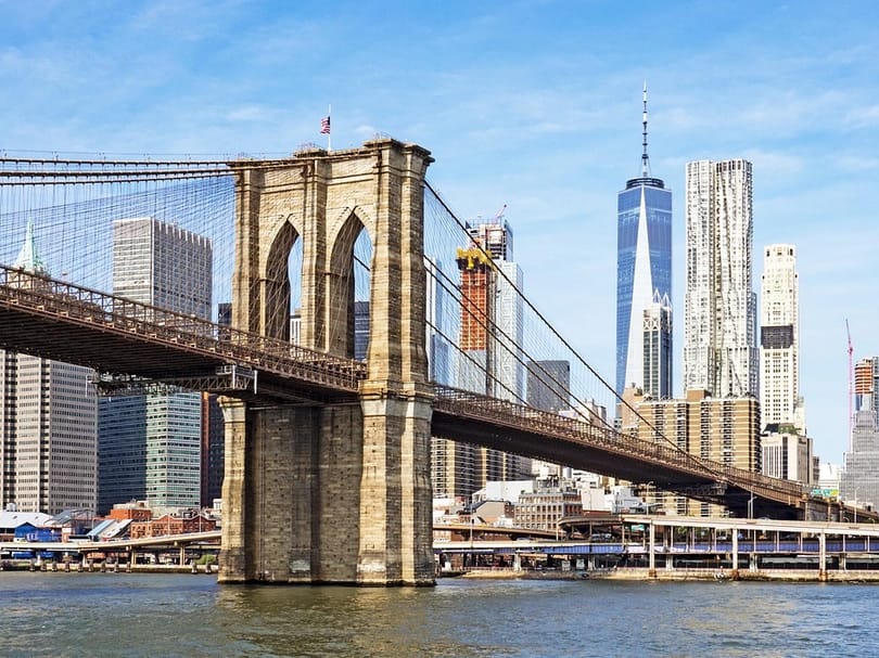 The Manhattan Bridge framed by brick buildings in DUMBO, with the New York skyline behind