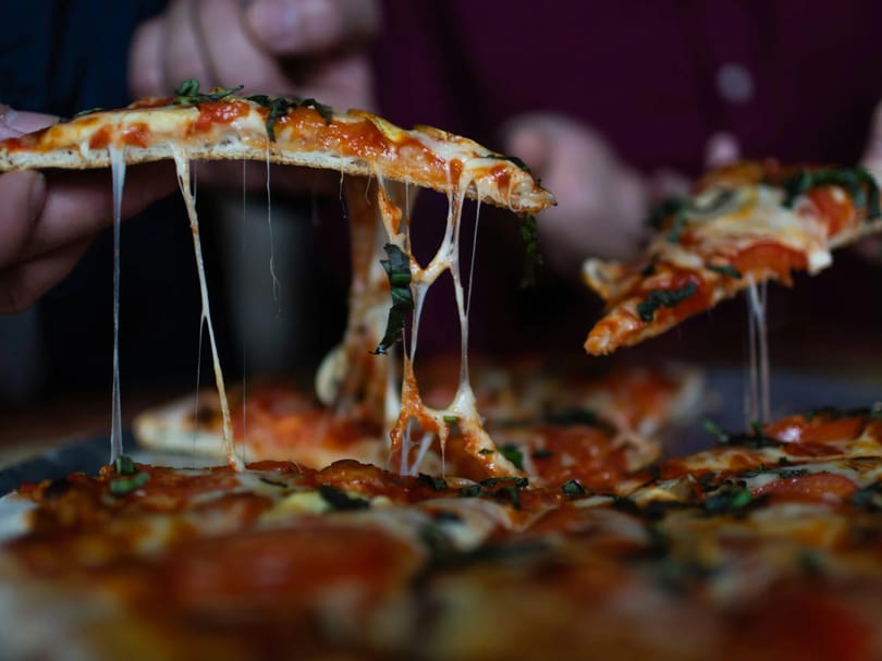 person picking sliced pizza
